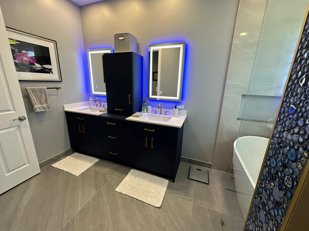 Navy double vanity with backlit LED mirrors and a freestanding tub